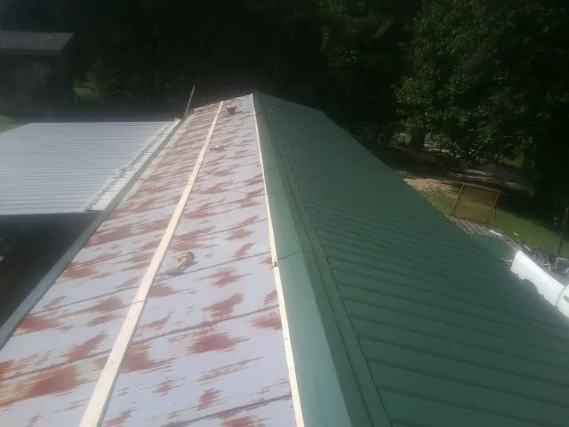 Old rusted panels beside newly installed green metal roofing — Wind Damage Roof Repair by Roofing Brothers in Colorado Springs
