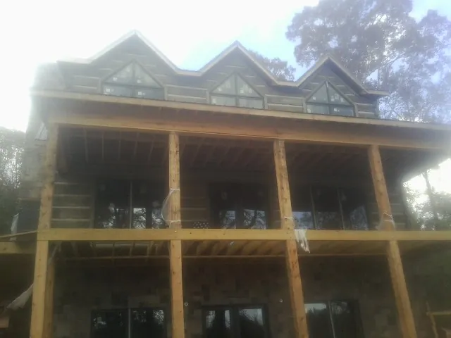 Dormers and porch framing on a large log home under construction — Roof Coating work by our crew in Colorado Springs