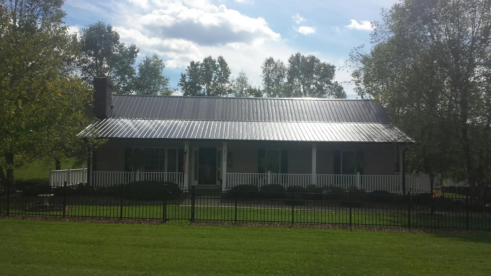 Gray metal roof on a brick ranch with a full width front porch — Gutter Guard Installation work by our crew in Colorado Springs