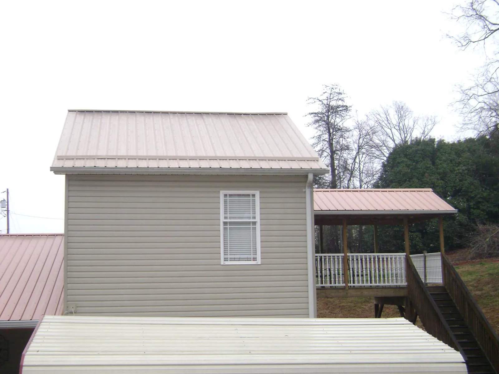 Tan metal roofs on a two story addition and attached porch, from a Roof Replacement job in Colorado Springs