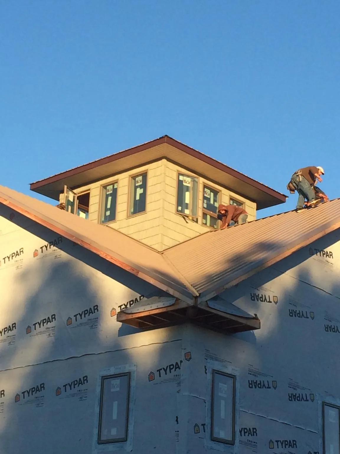 Roofers working around a rooftop cupola on a new metal roof at sunset — Roof Waterproofing in Colorado Springs by Roofing Brothers